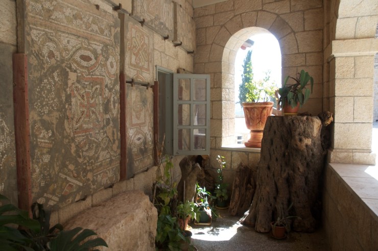 Het mozaïek met een rood kruis op de muur van de Stefanuskerk in Bet Gemal. Het mozaïek bevond zich oorspronkelijk in een Byzantijnse kerk op dezelfde plaats.  Foto’s: © Alfred Muller