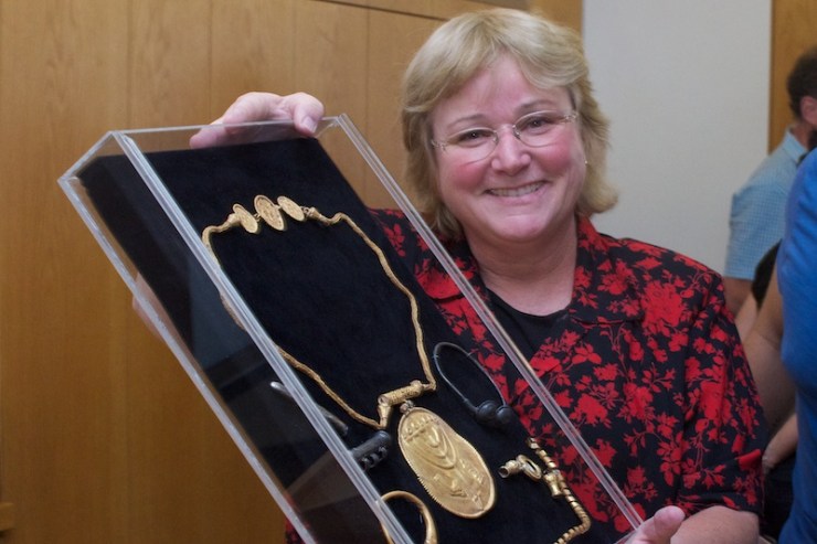 Dr. Eilat Mazar toont de medaille met de afbeelding van een menora, sjofar en torarol en andere zilveren en gouden voorwerpen. Foto: © Alfred Muller